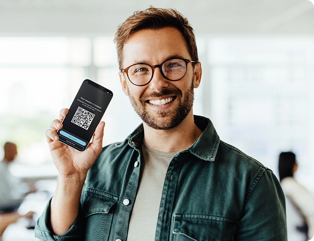 En leende man som håller i en smartphone där en QR-kod för att gå med i Vasco Audience visas.